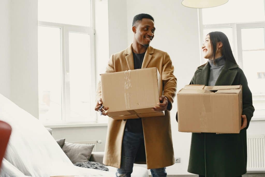 man and women holding moving boxes